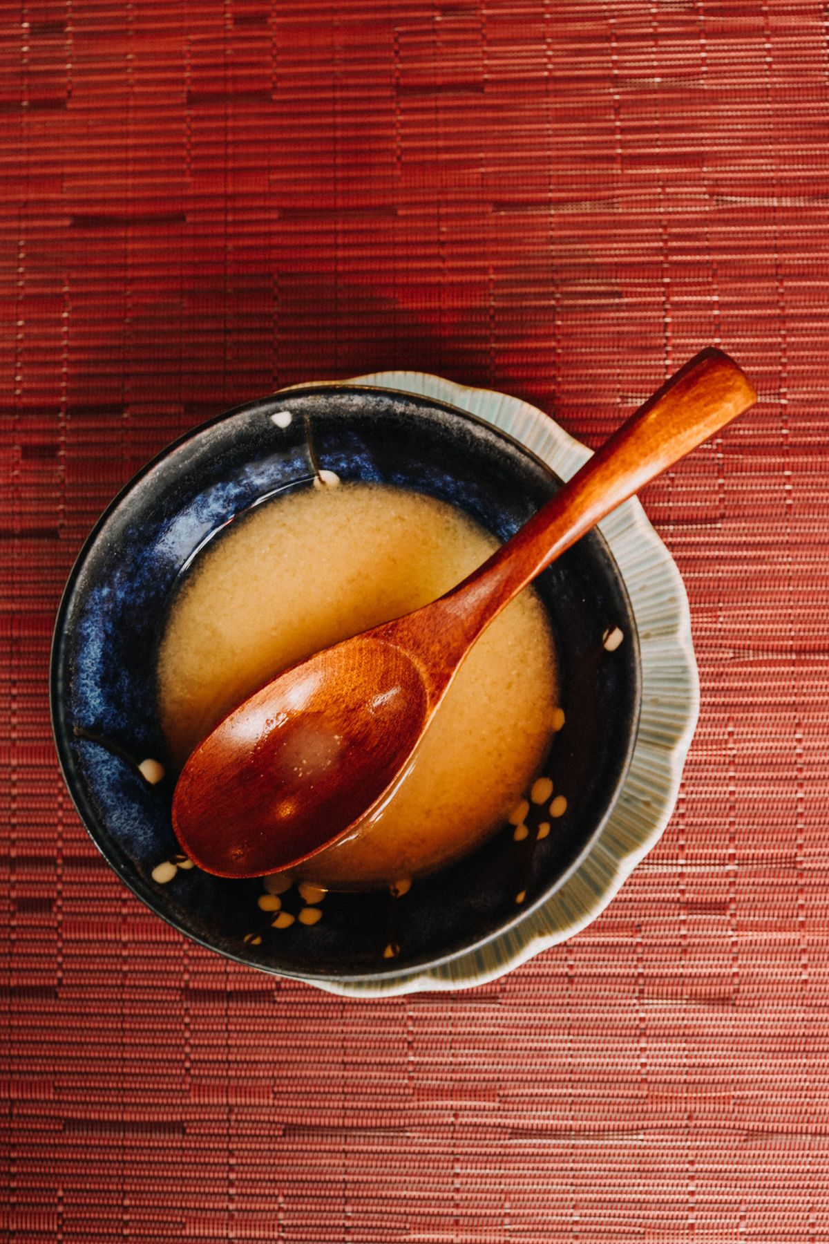 藍色の椀によそった味噌汁を木の匙ですくうところ