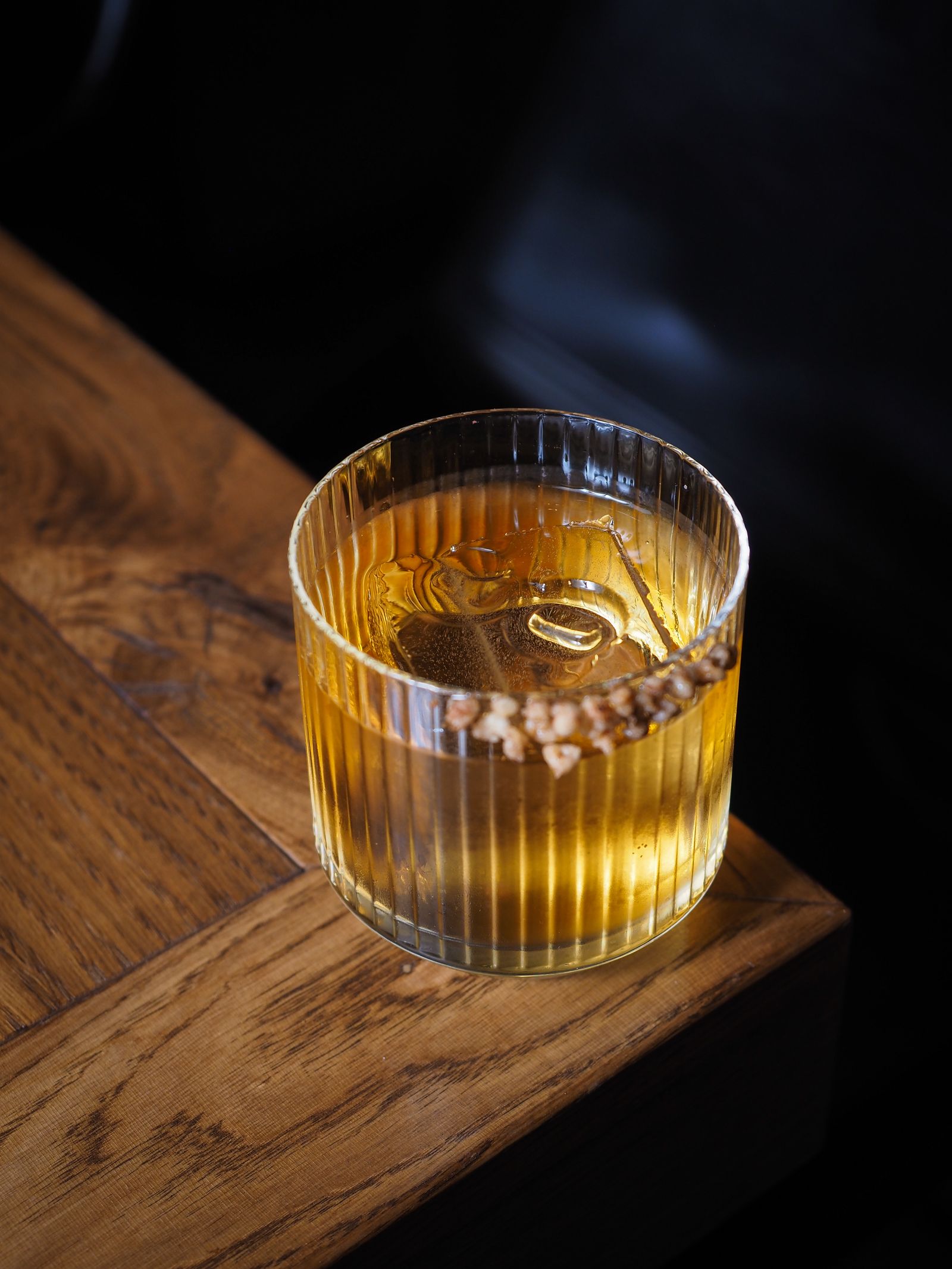 木のテーブルに置いた、琥珀色の焼酎ロックのグラス